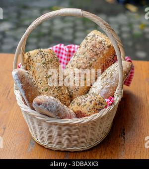 Basket of assorted artisan bread with seeds on wooden table, rustic homemade bakery concept Stock Photo