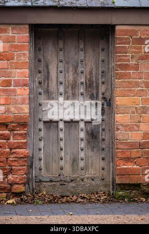 .rustic and historic-looking wooden door set into a red brick wall. Stock Photo