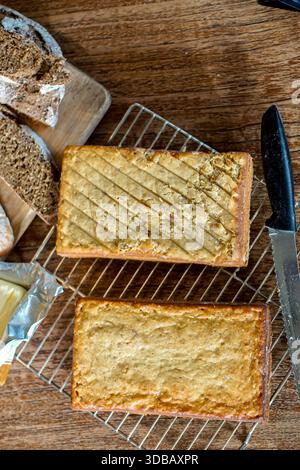 Homemade rectangular loaf cakes cooling on wire rack with bread and knife on wooden table Stock Photo