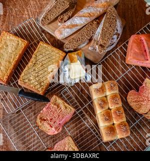 Assorted homemade bread with butter on cooling racks, rustic bakery food background Stock Photo