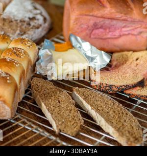 Assorted bread selection with butter on cooling rack, rustic bakery food background Stock Photo