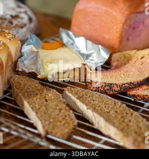 Assorted bread selection with butter on cooling rack, rustic bakery food background Stock Photo