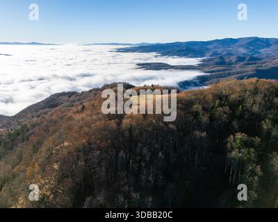 Aerial view of a stark contrast between the dark, dense forests and a sea of fluffy white clouds nestled in the valleys, Banská Bystrica, Slovakia. Stock Photo