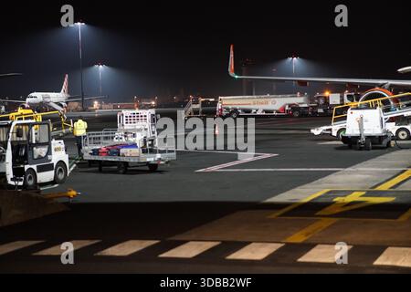 Nighttime ground operations on an airport apron with service vehicles and fuel trucks around parked aircraft.Nantes,France Stock Photo
