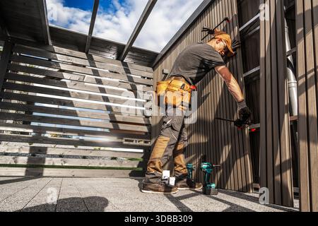 A worker is constructing a wall in an outdoor area under a blue sky. He uses tools and focuses on his task. Stock Photo