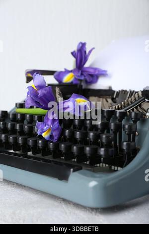 Vintage typewriter with paper sheet and purple flowers on light background Stock Photo