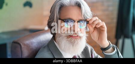 Mature man in eyeglasses with reflection of business statistics in office Stock Photo