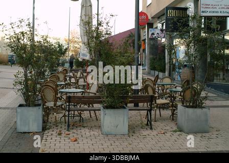 Pforzheim, Germany Dezember sunlit outdoor cafe with empty tables and wicker chairs, concrete planters Stock Photo