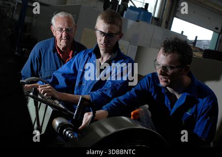Male & female engineering apprentices learning and receiving tuition from time-served and experienced engineers. Stock Photo