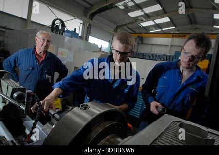 Male & female engineering apprentices learning and receiving tuition from time-served and experienced engineers. Stock Photo