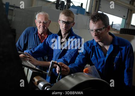 Male & female engineering apprentices learning and receiving tuition from time-served and experienced engineers. Stock Photo