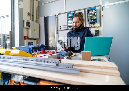 Female technician working with multimeter and laptop on renewable energy installation Stock Photo