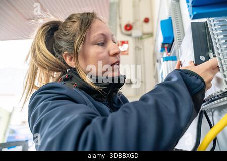 Woman adjusting a component in an industrial electrical panel, focusing on the task Stock Photo
