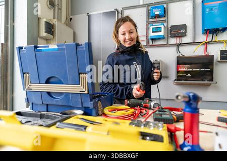 Woman engineer smiling while connecting wires in an off-grid solar power system Stock Photo