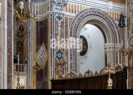 ornate marble pilasters and architectural details with colored inlays and a curved wooden choir stall in a historic european church interior with a sm Stock Photo