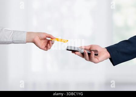 Contactless credit card and smartphone held by two people, representing mobile payment interaction and modern cashless transaction concept Stock Photo