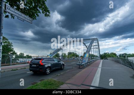 The Modersohnbrücke in Berlin, Germany, seen under a dramatic, overcast sky with dark storm clouds. Stock Photo