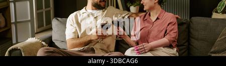 Header of Young Man and Young Woman Toasting Wine on Sofa Stock Photo