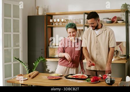 Young Woman and Young Man Preparing Homemade Pizza Together Indoors Stock Photo