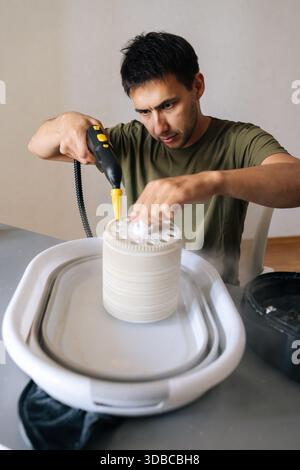 Male technician cleaning air humidifier filter with professional steam cleaner, removing dust and allergens for improved indoor air quality and home Stock Photo