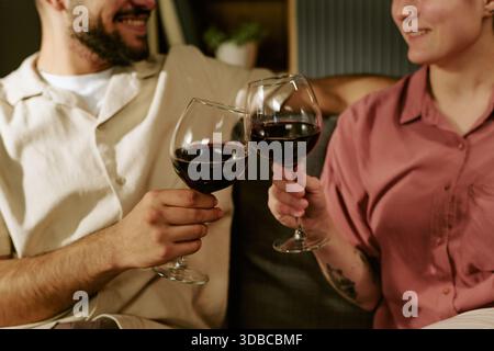 Young Man and Woman Toasting Wine Glasses and Smiling Together Stock Photo