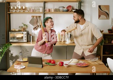 Young Woman and Young Man Laughing While Preparing Pizza Together Stock Photo