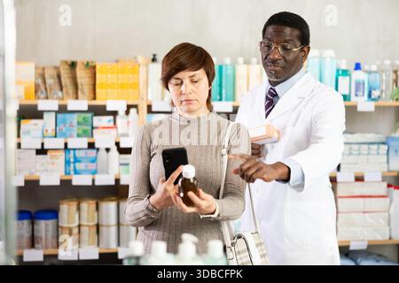 Woman buyer scans syrup qr code with man pharmacist Stock Photo