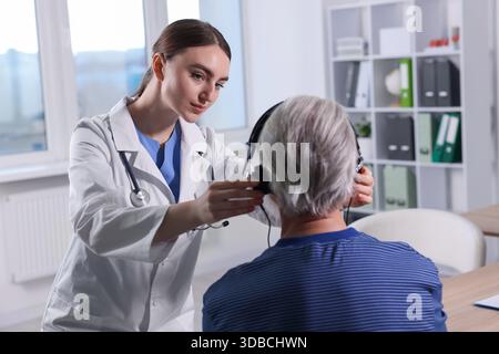 Hearing test. Doctor adjusting patient's audiometric headphones in clinic Stock Photo