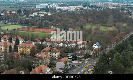 View of a residential area with a sports field, autumn trees, and surrounding forest, seen from the Völkerschlachtdenkmal looking southeast. Stock Photo