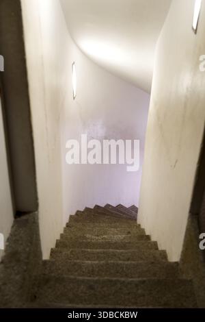 A narrow, curved staircase with illuminated walls inside a building, creating a flowing and modern architectural element. Stock Photo