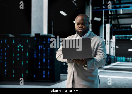 Data center computer scientist using laptop to protect servers from exploitable software vulnerabilities, auditing systems. Server farm employee looking for bugs slowing down rigs Stock Photo
