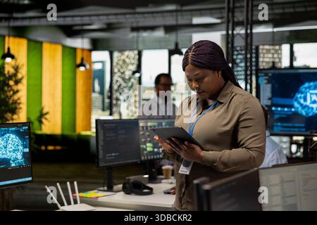 Programmer in office automating repetitive tasks using AI scripts on tablet. IT professional using artificial intelligence technology on device to speed up feature implementation Stock Photo