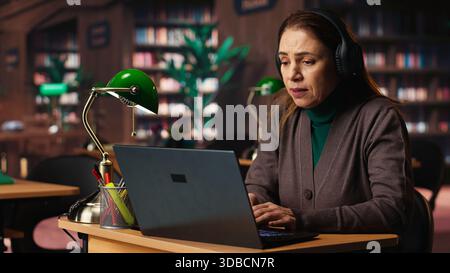 Mature woman involved in a remote classroom experience via online platform, using wireless internet to study a university course and chatting with his teacher. Reviewing project materials. Stock Photo