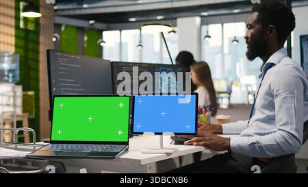Software developer using AI on isolated screen laptop and tablet to optimize performance and forecast issues. IT expert in office training machine learning models using chroma key notebook, camera A Stock Photo