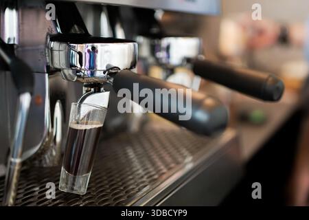Fresh espresso shot brewing from professional coffee machine in café, close up coffee making process Stock Photo