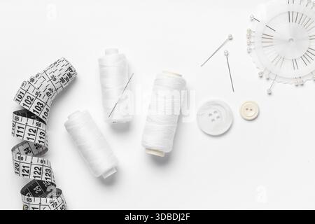 Spools of thread with ball pins, buttons and measuring tape on white background Stock Photo
