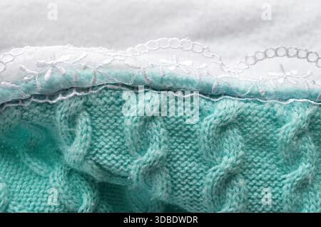 Aqua blue-green knitted fabric with visible braided stitches and a piece of white lace. Elegant and charming, perfect for interior design or fashion a Stock Photo