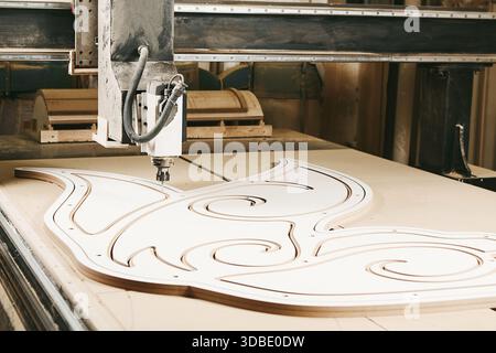 Numerically controlled woodworking machine cuts rounded complex lines on the canvas. Computer numerical control. CNC. Stock Photo