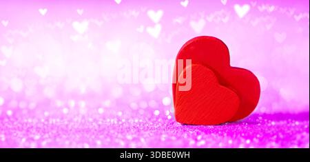 Two red hearts against a shimmering  pinky bokeh background. Valentine's Day, Wedding and date concept. Stock Photo