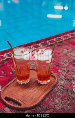 Two glasses of Iranian traditional drink on a beautiful red carpet; there are pieces of ice and rose flowers in them. Stock Photo