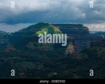Aerial view of a mountain range, its slopes painted with vibrant green hues under a dramatic sky, Nashik, Maharashtra, India. Stock Photo