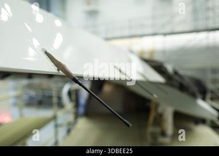 Engineers meticulously inspect the wing of an aircraft, using precision instruments to ensure accuracy and quality in a high-tech aerospace setting du Stock Photo