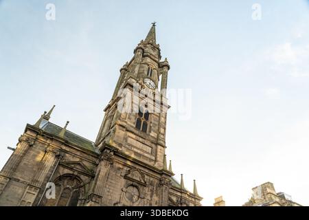 View of striking Tron Kirk stone church tower with a clock face rising towards the pale blue sky in the old town, Edinburgh, Scotland, United Kingdom. Stock Photo