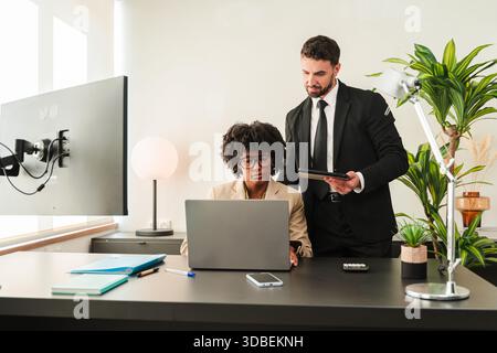 Two focused business professionals working together on a laptop in a corporate environment for optimal productivity and effective teamwork during an Stock Photo