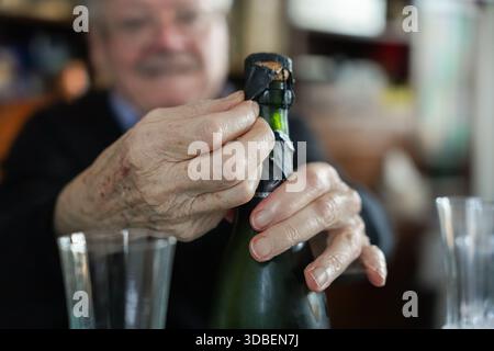 Senior man opening champagne bottle Stock Photo