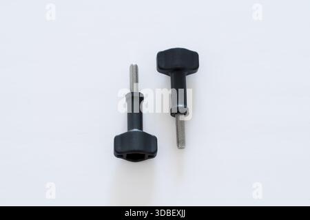 Close-up macro of two thumb screws with a black head positioned opposite on a clean white background. Ideal for hardware, engineering, product design, Stock Photo