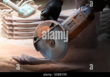 A worker cuts a red  ceramic roof tiles for a house roof Stock Photo