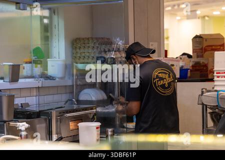 Chef prepares fresh pasta behind a glass counter in a bustling Singapore restaurant kitchen. Editorial capture of food service, culinary work, and res Stock Photo