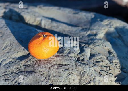 Cluster of red cherry tomatoes in a folded brown paper bowl on natural rock background, showcasing vibrant color and fresh appeal. Stock Photo
