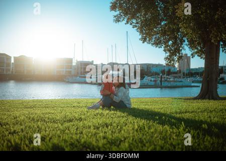romantic couple by marina, couple sharing picnic and embracing during serene sunset Stock Photo